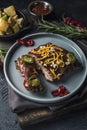 Grilled pork ribs in tomato sauce with chili pepper on a dark ceramic plate and baked potatoes in a bowl Royalty Free Stock Photo