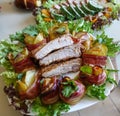 Grilled pork ribs on a white plate with greens, lettuce and meat rolls