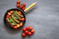 Grilled pork sausages or bangers in cast iron skillet or frying pan with tomatoes with dill and green onions Royalty Free Stock Photo