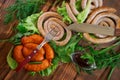 Grilled pork sausages, knife, fork, sauce in a sauce-pan and corn buns on a wooden surface of pine boards. Nearby are lettuce, Royalty Free Stock Photo