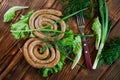 Grilled pork sausages lie on a wooden table with greens: lettuce, dill, parsley and onion. View from above. Picnic - barbecue