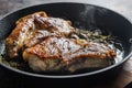 Grilled pork steak on the bone with seasonings on hot pan with smoke side view close up horisontal Royalty Free Stock Photo
