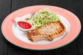 Grilled pork steak with green salad of cabbage and peas in plate on dark background. Hot Meat Dishes. Royalty Free Stock Photo