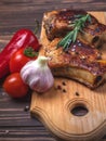 Grilled pork steaks and vegetables on a rustic wooden table. Grilled meat on the bone with spices Royalty Free Stock Photo