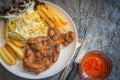 Grilled pork steaks on white plate with salad and french fries and ketchup on stone background Royalty Free Stock Photo
