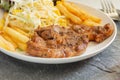 Grilled pork steaks on white plate with salad and french fries and ketchup on stone background Royalty Free Stock Photo