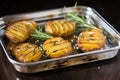 grilled potatoes garnished with rosemary on a mirrored serving tray