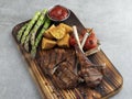 Grilled rack lamb chops on a wooden board with asparagus, red sauce, potatoes Royalty Free Stock Photo