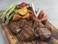 Grilled rack lamb chops on a wooden board with asparagus, red sauce, potatoes Royalty Free Stock Photo