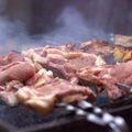 Raw pork entrecotes with a layer of grilled fat for Easter. Smoke comes from hot coals