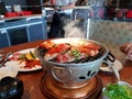 Grilled raw sliced beef and pork on the hot stainless steel stove with smoke and waiter walking to serve food background Royalty Free Stock Photo