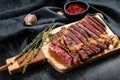 Grilled rib eye, ribeye steak on a chopping Board, medium rare. marbled meat. black background. top view