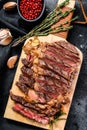 Grilled rib eye, ribeye steak on a chopping Board, medium rare. marbled meat. black background. top view