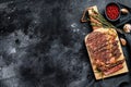 Grilled rib eye, ribeye steak on a chopping Board, medium rare. marbled meat. black background. top view. Copy space