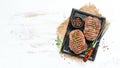 Grilled ribeye beef steak, herbs and spices on a white wooden background. Top view.