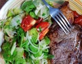 Grilled Ribeye beef steak with a large portion of fresh salad on a color plate