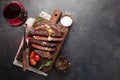 Grilled ribeye beef steak with red wine, herbs and spices on a dark stone background. Top view with copy space for your Royalty Free Stock Photo