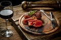 Grilled ribeye beef steak with red wine, herbs and spices on wooden table Royalty Free Stock Photo