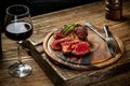 Grilled ribeye beef steak with red wine, herbs and spices on wooden table Royalty Free Stock Photo