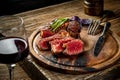 Grilled ribeye beef steak with red wine, herbs and spices on wooden table Royalty Free Stock Photo