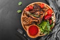 Grilled Ribeye Steak on bone and vegetables with fresh salad and bbq sauce on cutting board over black stone background. Hot Meat Royalty Free Stock Photo