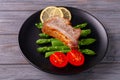 Grilled ribs with green asparagus, tomatoes and lemon on a plate Royalty Free Stock Photo