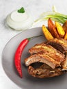 Grilled ribs with idaho potatoes and vegetables on the plate, on the grey background. Shallow depth of field. Vertical orientation Royalty Free Stock Photo