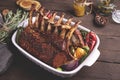 Grilled roasted rack of veal lamb chops with vegetables in ceramic baking dish.