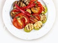 Grilled roasted vegetables on a white plate.  Sweet peppers, tomatoes, zucchini, eggplant. Top view Royalty Free Stock Photo