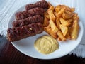 Grilled romanian traditional food meat rolls called mititei, mici - close-up with french fries and mustard Royalty Free Stock Photo