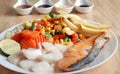 Grilled salmon fish and baked cod fish decorated with various vegetables corn carrot peas lemon french fries and sauces Royalty Free Stock Photo