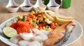 Grilled salmon fish and baked cod fish decorated with various vegetables corn carrot peas lemon french fries and sauces Royalty Free Stock Photo