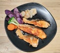 Grilled salmon fish dressing decorated various vegetables corn carrot peas purple potato fries and sauces on black flat plate