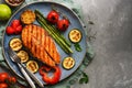 Grilled salmon fish with vegetables zucchini, asparagus, tomato, sweet pepper on a plate, gray background. Top view, flat lay,copy Royalty Free Stock Photo