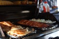 Grilled salmon on the flaming grill. Fresh raw salmon fillet on wooden board wrapped in foil cooking on grill.