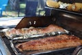 Grilled salmon on the flaming grill. Fresh raw salmon fillet on wooden board wrapped in foil cooking on grill.