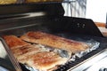 Grilled salmon on the flaming grill. Fresh raw salmon fillet on wooden board wrapped in foil cooking on grill.