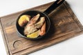 Grilled salmon with lemon slice, baked potato and carrot served in a frying pan on a rustic wooden board Royalty Free Stock Photo