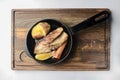 Grilled salmon with lemon slice, baked potato and carrot served in a frying pan on a rustic wooden board Royalty Free Stock Photo