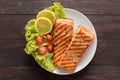 Grilled salmon with lemon,tomato on the wooden background Royalty Free Stock Photo