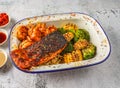 Grilled salmon and shrimps with noodles, grilled corn and broccoli served in isolated on grey background top view of singaporean Royalty Free Stock Photo