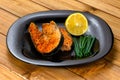 Grilled salmon steak with lemon slice and herbs in a black plate on a wooden background Royalty Free Stock Photo