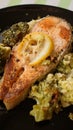 Grilled salmon steak served on black plate with vegetable garnish from broccoli Royalty Free Stock Photo