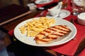 Grilled Salmon steak served with french fries chips, on ÃÂ° wooden table with red tablecloth, close-up view with blurred Royalty Free Stock Photo