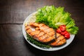 Grilled salmon steak served with grilled tomatoes, salad, lemon sliced, pepper seeds, rosemary, parsley Royalty Free Stock Photo