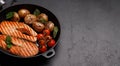 Grilled salmon steaks and potatoes sizzling in a frying pan Royalty Free Stock Photo