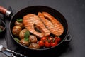 Grilled salmon steaks and potatoes sizzling in a frying pan Royalty Free Stock Photo