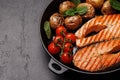 Grilled salmon steaks and potatoes sizzling in a frying pan