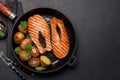 Grilled salmon steaks and potatoes sizzling in a frying pan Royalty Free Stock Photo