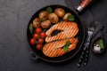 Grilled salmon steaks and potatoes sizzling in a frying pan